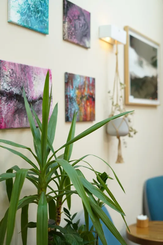 Cafe art wall with colourful paintings and greenery