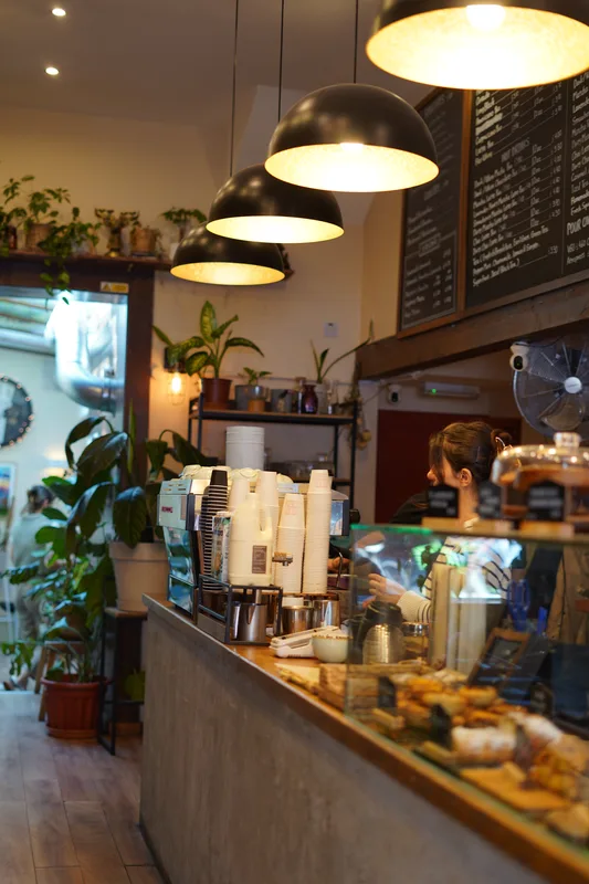 Coffee counter with pastries, plants and pendant lights